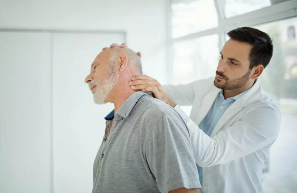 Medic examining an old man with neck sprain