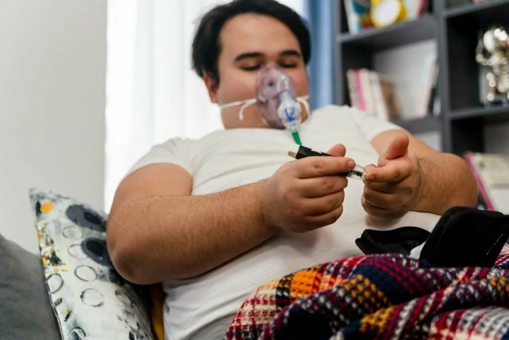 Image of a young man suffering from morbid obesity measuring his blood sugar level.